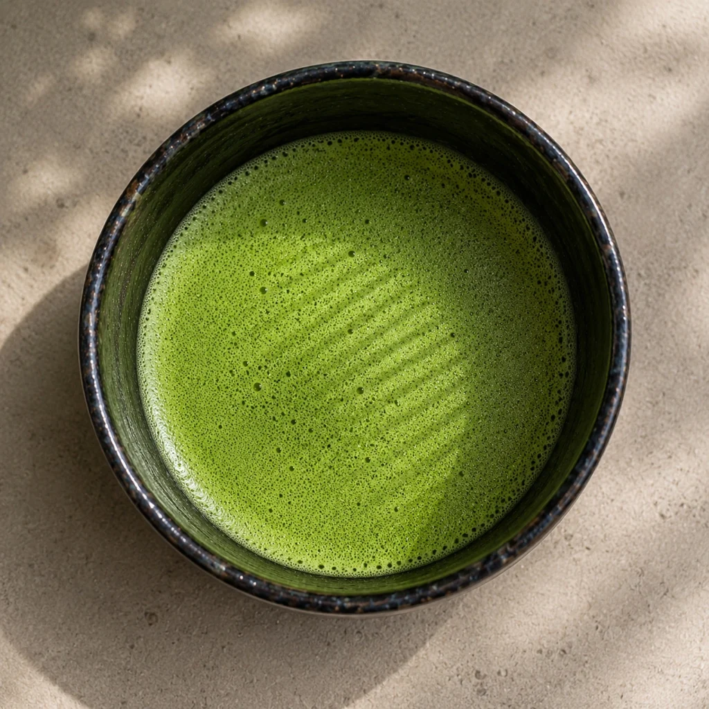 Bowl of matcha seen from above showing bright green foam circle with chasen whisk pattern zen daily practice