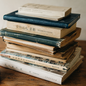 Stack of books piled on wooden surface with cup of tea tsundoku Japanese art of collecting unread books